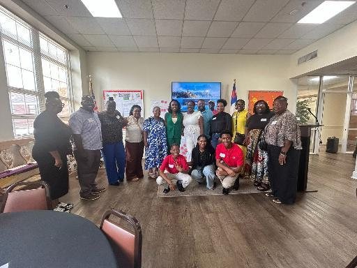 A large group of residents and partners stands together in a community room after the August 2026 charrette.